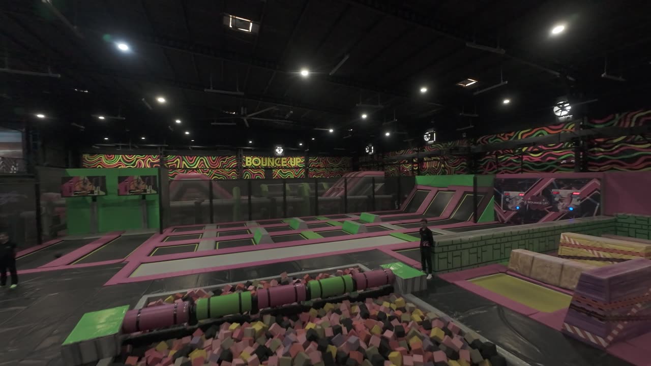 The trampoline arena: green courts, pink pads, foam pit