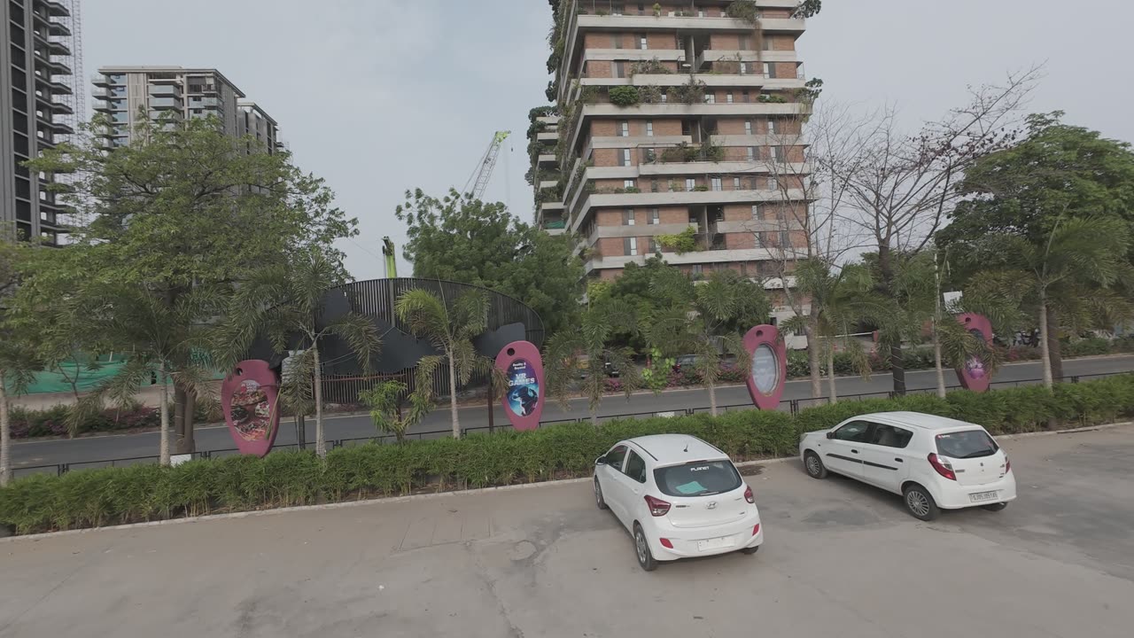 The street outside BounceUp on Ambli Bopal Road, pink art panels along the fence